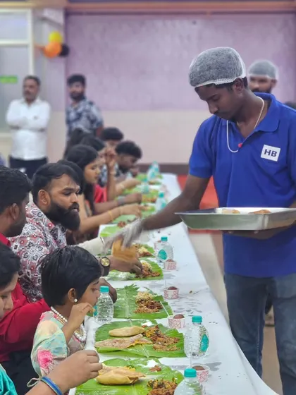 Our server attending to guests, including young children, during a banana leaf service. We ensure everyone feels comfortable and well-cared for.