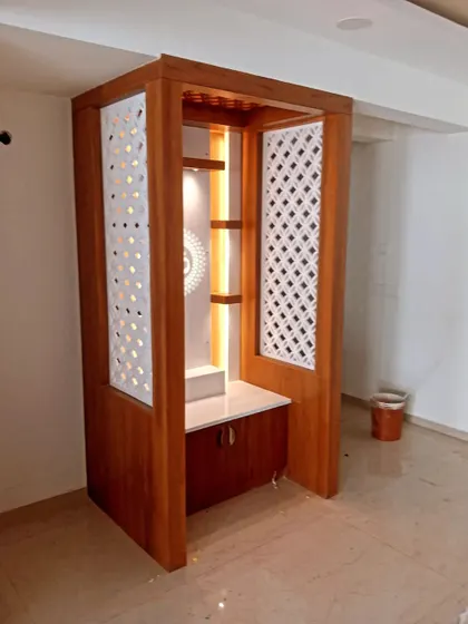 A custom-built wooden pooja unit with a beautiful polish. The finish complements the intricate jali work and integrated lighting.