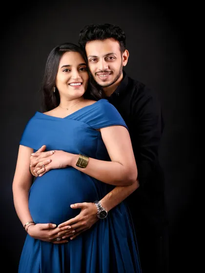A simple and elegant couple's portrait against a solid black background. This style puts all the focus on your expressions and the beautiful shape of the baby bump.