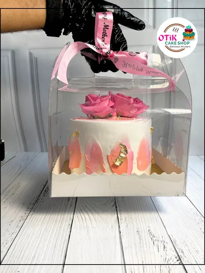 An elegant Mother's Day cake with pink rose decorations, presented in a clear carrying case with a "Happy Mother's Day" ribbon. It's a gift that's as beautiful as it is delicious.