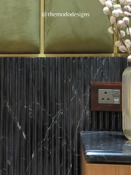 Texture plays a crucial role in creating depth. Here, we layered olive green upholstered panels with fluted black marble, creating a sophisticated and tactile feature wall.