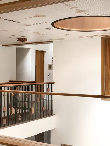 A view of the upper-level corridor in Kolam Pop, showing the mosaic ceiling, the custom balustrade, and the slatted wooden window screens.