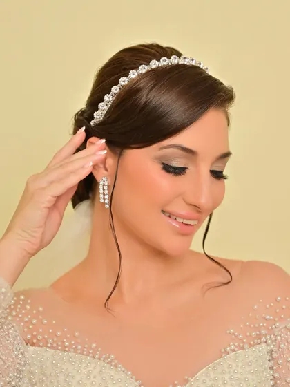 A gentle smile from the bride, her makeup looking flawless. The elegant updo is adorned with a simple, sparkling tiara.