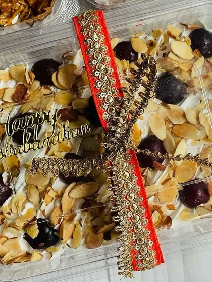 A close-up of the Cherry Almond Tres Leches tub from my Rakhi collection. It comes with a "Happy Raksha Bandhan" topper and is tied with a traditional decorative ribbon.