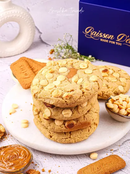 A stack of white chocolate chip cookies, styled with Biscoff spread and biscuits for a decadent look.