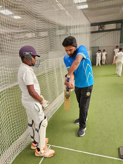 A young batsman receives personalized instruction on his grip and form. This close attention to detail helps break bad habits early.