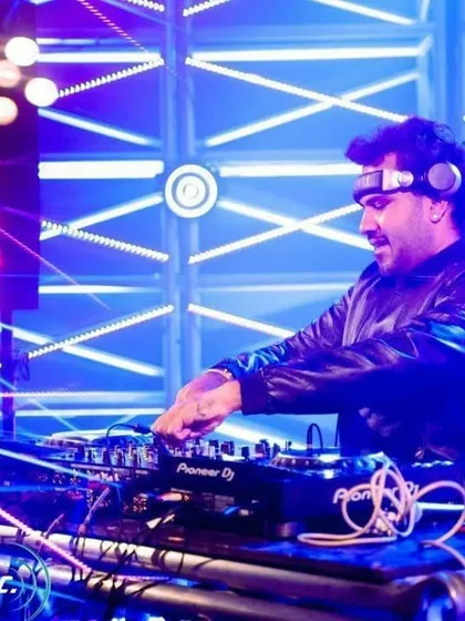 At the console with a complex grid of lights behind me. As a VDJ, I use lighting and visuals as another instrument to build energy and create unforgettable moments.