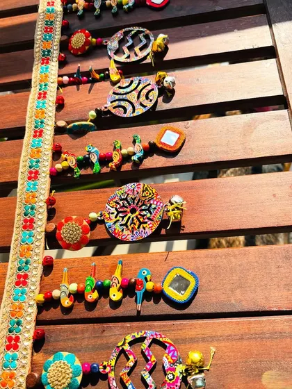 The 'Rang-Tarang' toran laid out to show its intricate details. The psychedelic printed discs alternate with rows of colorful parrots and handmade mirrors.