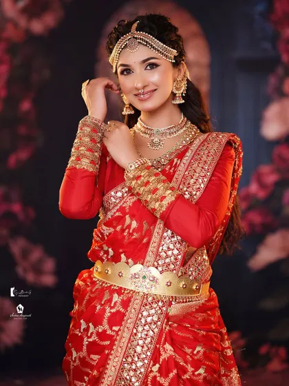 The complete look, showing how the hairstyle works with the red saree and gold jewelry.