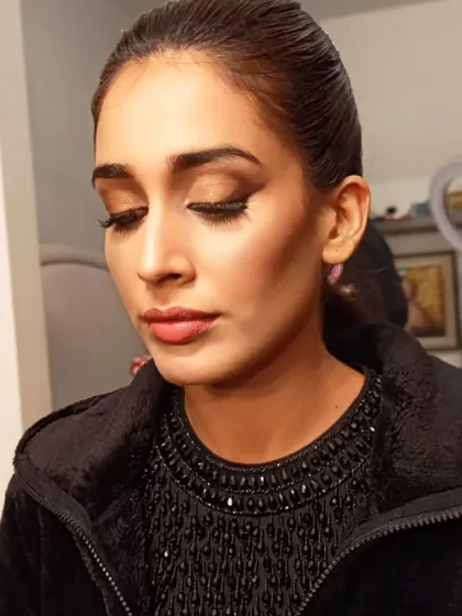 A sharp, winged eyeliner and sculpted cheekbones define this chic look. The hair is pulled back into a sleek ponytail, creating a modern and powerful silhouette.