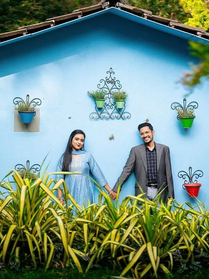 A fun and colorful shot of a couple posing against a bright blue wall.