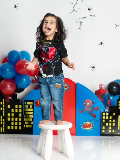 This little hero is ready to save the day, standing tall on a stool to get a better view of the city.