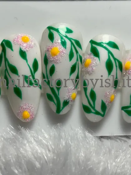 A set of hand-painted press-on nails with a delicate green vine and flower design. Learn to make these in my nail art course.
