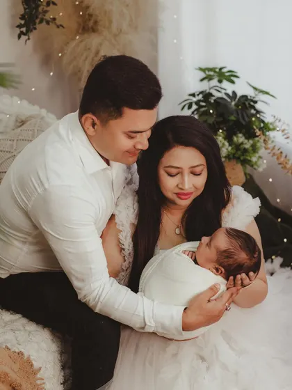 A loving portrait of a mother and father cradling their newborn together, surrounded by the warm and inviting decor of the studio.