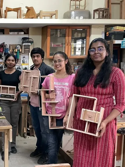 A group of interior design students proudly displaying the complex shelf designs they built in a single day.