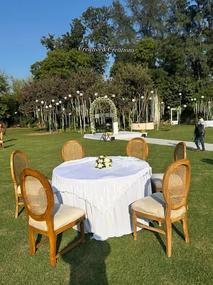 Simple and elegant guest seating for an outdoor daytime event. The white tablecloths and classic wooden chairs complement the natural surroundings perfectly.