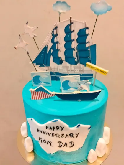 An ocean-themed anniversary cake. The design features a sailboat and waves, symbolizing a journey together. It's a unique and beautiful theme for an anniversary.