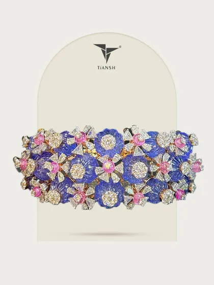 Each bloom in this bracelet tells a story. Carved blue petals, diamond dew, and pops of pink sapphire come together in a masterpiece of color and craft, where elegance meets bold imagination.