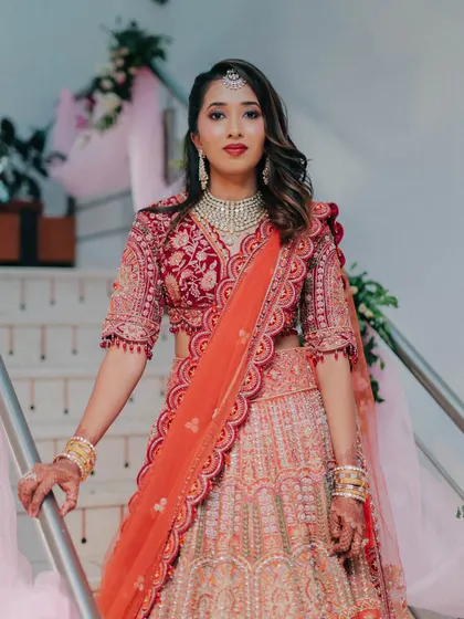 A full-length view of this stunning red and orange lehenga. The makeup is bold and confident, perfect for a bride who wants to make a statement.