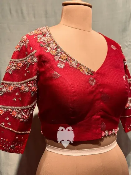 A pink zari kota blouse with intricate floral designs featuring delicate French knots on the neckline and sleeves.