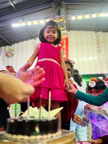 Children see magic because they look for it. A birthday girl stands by her cake, surrounded by friends, in a moment of pure party magic.