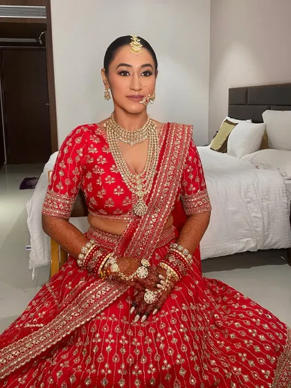 A classic bridal look for Kritika in a stunning red lehenga. The makeup is clean and flawless with defined eyes, paired with a sleek bun for a regal and polished finish.