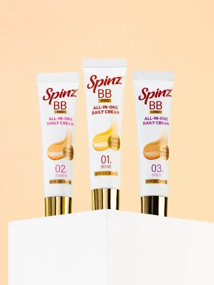 A clean, minimalist shot of three Spinz BB cream tubes on a white pedestal. This is a classic e-commerce photo that clearly displays the product and its different shades.