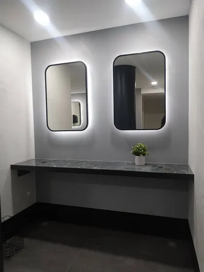 This view shows the clean, minimalist design of the grooming area. The simple material palette of gray walls and dark stone provides a calm and uncluttered environment for members post-workout.