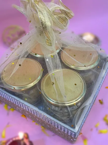 A beautifully wrapped tray hamper for Diwali, containing four jars of assorted nuts and cookies.