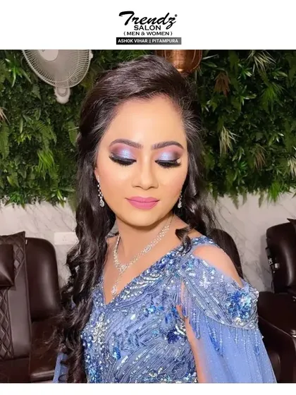 A glamorous look perfect for a cocktail party or reception. The makeup features a dramatic blue and purple smokey eye, paired with a soft pink lip to balance the look in her beaded blue gown.