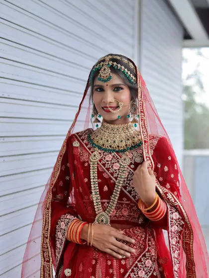 A smiling bride in a red lehenga, a look created by one of my students. The makeup is fresh and radiant, perfect for a daytime wedding ceremony.