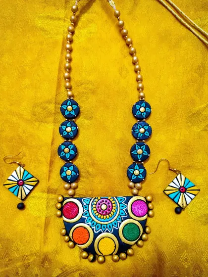 This multi-colored necklace features a unique pendant with five distinct color circles. The design is modern and playful, and it comes with kite-shaped earrings.