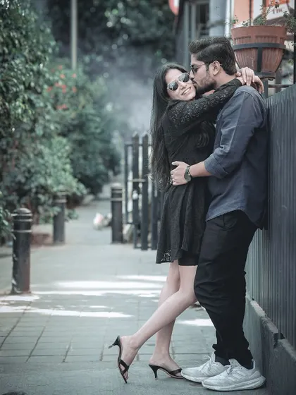 An intimate embrace on a city sidewalk, capturing a tender moment in a casual, urban setting.