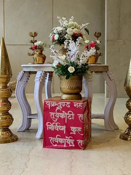 A traditional decor arrangement with brass elements, red roses, and a custom-printed cube featuring a Sanskrit shloka, blending spirituality with beautiful design.