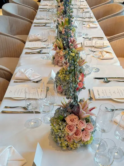 An overhead view of the impeccably set dining table for the Jimmy Choo event, showcasing the symmetrical arrangement of floral centerpieces and place settings.