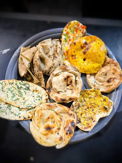 A platter showcasing the incredible variety of my handcrafted Indian breads. Each one, from the flaky parathas to the soft naans, is made fresh for your event.