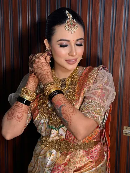 A candid moment of the bride adjusting her earring. This shot highlights the intricate details of her henna and the flawless makeup.