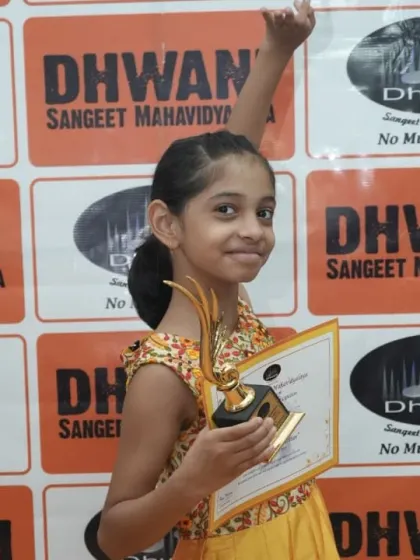 A young student raises her hand in victory, holding her trophy. We celebrate the spirit and enthusiasm of our talented performers.