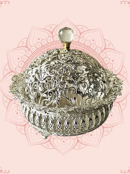 A stunning silver-domed container with intricate cutwork. This piece is ideal for serving dry fruits or sweets and makes for a luxurious and traditional gift.