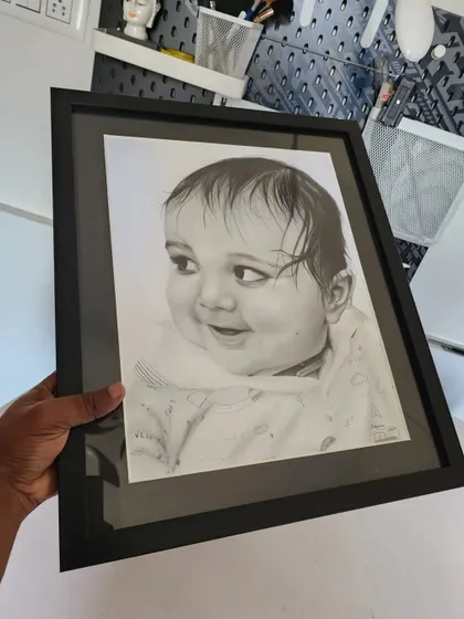 The finished baby portrait, held up in a simple black frame.
