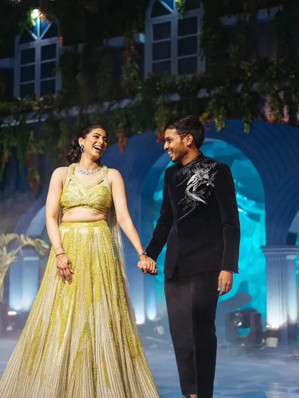 The couple's grand entrance to their Sangeet, with stage lights and smoke creating a dramatic and exciting start to the evening.