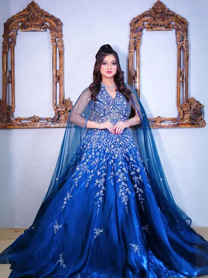 A full-length shot of our royal blue ball gown with silver floral embroidery and dramatic cape sleeves.