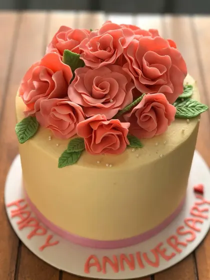 A simple and elegant anniversary cake with a bouquet of hand-piped pink roses.