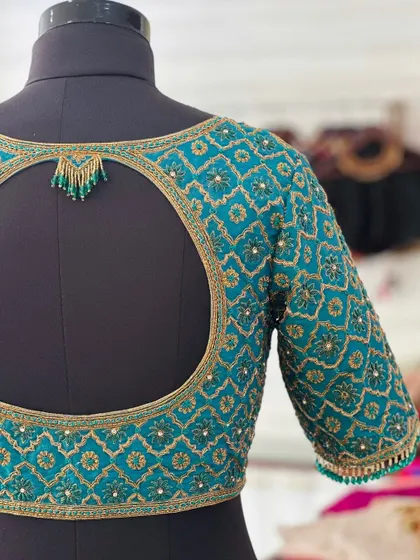 A teal blouse with a geometric embroidered pattern and a keyhole back.