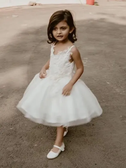 A candid shot of a little girl in her white flower girl dress, showing the beautiful movement of the full tulle skirt.