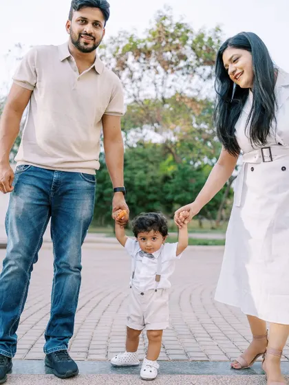 Parents helping their one-year-old take his first steps. A classic milestone moment captured beautifully.