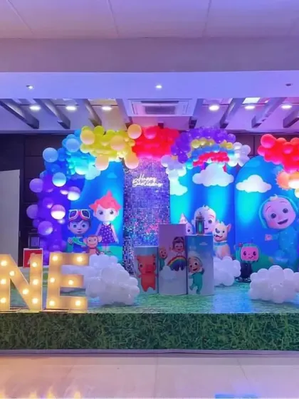 This Cocomelon theme brings the show to life with a backdrop of blue skies and fluffy balloon clouds, creating a cheerful and bright setting for a first birthday party.