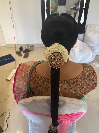 A close up of a traditional braid with a large, ornate 'Jada Billa' and a full 'Gajra' of jasmine flowers.