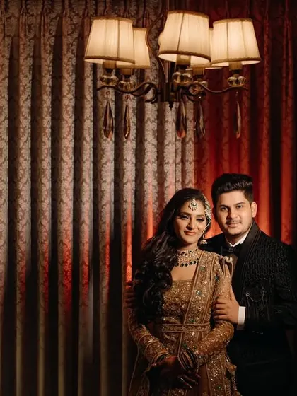 A classic, formal portrait of the couple. The elegant lighting and their poised stance create a timeless image that feels both sophisticated and full of warmth.