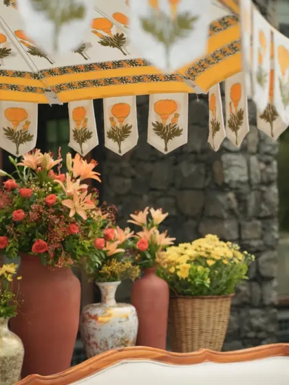 A close-up of the hand-blocked umbrella and terracotta vases filled with lilies and roses, adding a touch of elegance to the outdoor lounge.